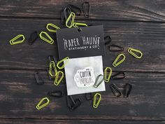 some black and yellow paper clips laying on top of a wooden table next to each other