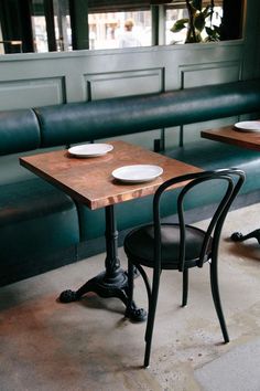 two tables with plates on them sit in front of green booth seats at a restaurant