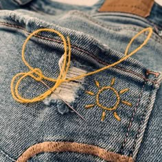 a pair of jeans that have been stitched together with yellow thread and some scissors