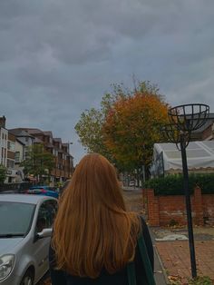 a woman standing next to a parked car in front of a basketball hoop on a street