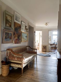 a wooden bench sitting in the middle of a living room with pictures on the wall