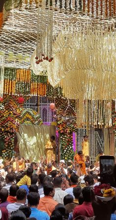 a group of people standing in front of a stage with chandeliers hanging from the ceiling