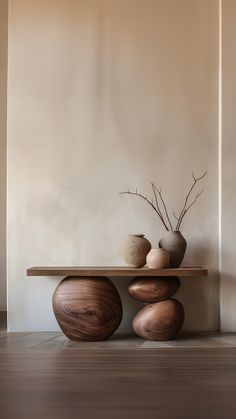 three vases sitting on top of a wooden table in front of a white wall