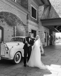 a bride and groom standing in front of a vintage car