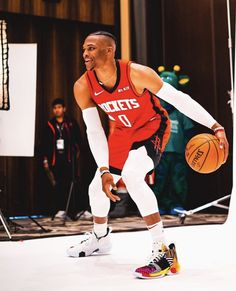 a man holding a basketball while standing on top of a basketball court with other people watching