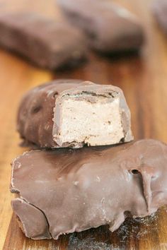 two pieces of chocolate covered marshmallows sitting on top of a wooden table