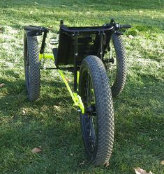 the bike is parked in the grass with two wheels attached to it