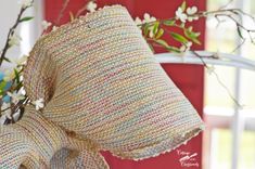 a close up of a pillow on a chair with flowers in the back ground and a red door behind it