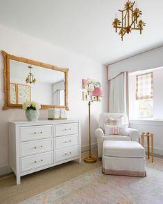 a living room with white furniture and a large mirror on the wall above it's dresser