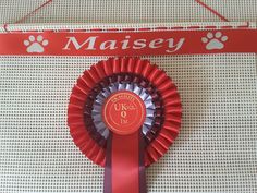 a red rosette with a paw print on it and a sign that says maisey