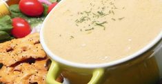 a bowl of soup next to crackers and vegetables