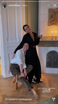 two people posing for a photo in front of a fireplace