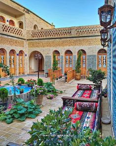 an outdoor courtyard with potted plants and rugs on the ground in front of a pool