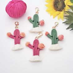 three cactus keychains with tassels and a ball of yarn next to them