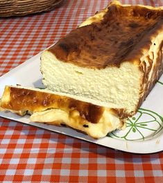 a piece of cheesecake on a plate sitting on a checkered tablecloth with a basket in the background