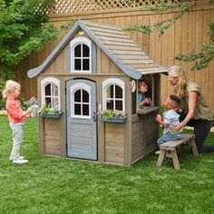 a group of people standing around a small wooden house