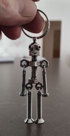 a person holding onto a metal robot keychain