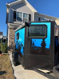 a blue and black truck parked in front of a house with trees on the side