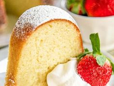 a slice of pound cake with whipped cream and strawberries on the side, ready to be eaten