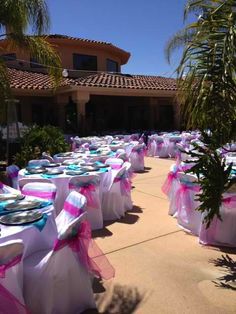 tables and chairs covered with pink and blue cloths are set up in front of a house