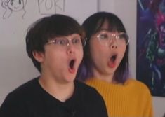 two people standing next to each other with their mouths open