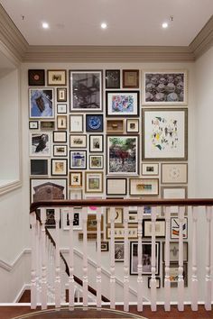 a staircase with many framed pictures on the wall above it and a banister in front of