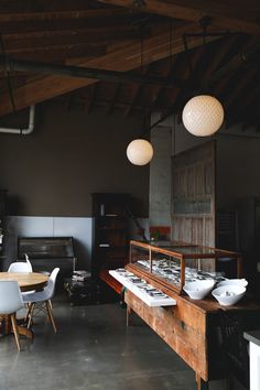 an industrial kitchen and dining room with wood beams, white chairs, and wooden table