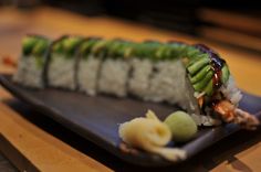 a sushi roll is sitting on a black plate