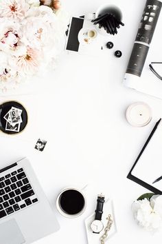 a laptop computer sitting on top of a white desk next to flowers and other items