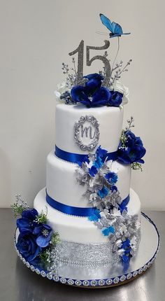 a white cake with blue flowers and silver decorations