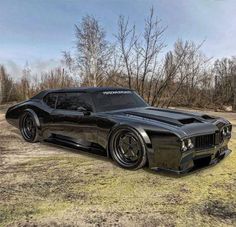 a black car parked on top of a grass covered field