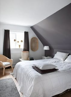 a bed sitting in the middle of a bedroom under a slanted ceiling next to a window