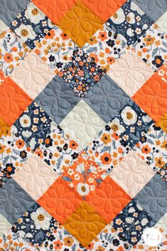 an orange and blue quilt with flowers on it's edges, in the center