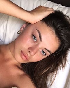 a beautiful young woman laying on top of a bed