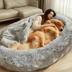 a woman laying on top of a dog bed