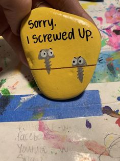 someone is holding up a painted rock that says sorry, i screwed up on it