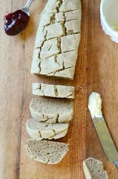 sliced bread and butter on a cutting board next to a knife with jam in the background