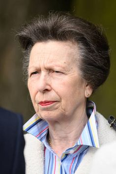 an older woman with short hair wearing a blue and white striped shirt looking off to the side