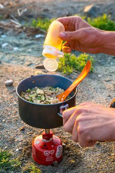 a person pouring something into a pot on top of a fire hydrant in the dirt