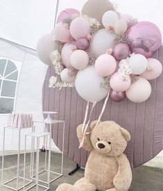 a teddy bear sitting in front of a bunch of balloons