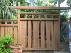 a man standing in front of a wooden fence next to a potted planter