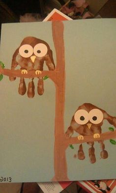 two brown owls sitting on top of a tree next to a paper plate with leaves