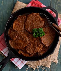 a skillet filled with meat and broccoli on top of a wooden table