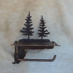 two metal pine trees sitting on top of a towel rack next to a toilet paper dispenser