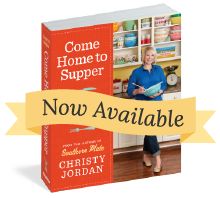 a woman standing in front of a book with the title come home to supper now available