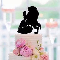 a wedding cake with the silhouette of a horse and rider on top, surrounded by flowers