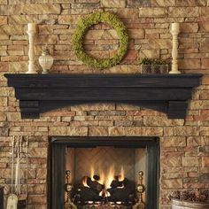 a brick fireplace with a wreath above it and candles on the mantel over top