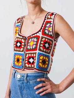 a woman is wearing a crocheted top and denim skirt with her hands on her hips