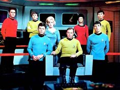 a man sitting on top of a blue box next to other men in star trek uniforms