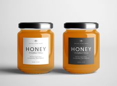 two jars of honey sitting side by side on a white surface, one with a label that says honey